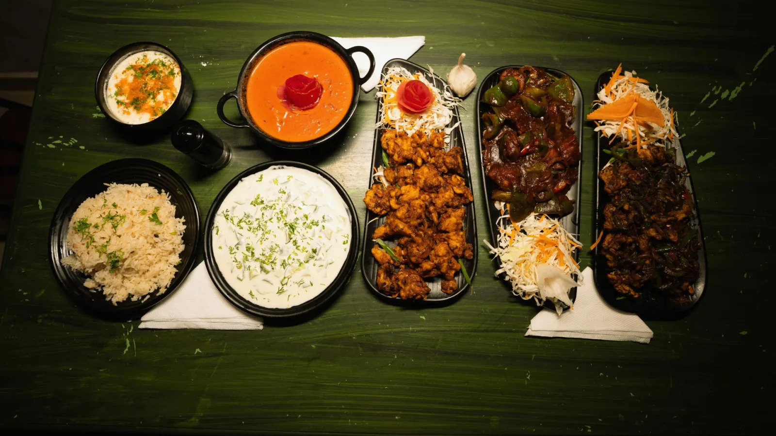 A spread of freshly prepared dishes laid out on a green wooden table at Hasu Stay