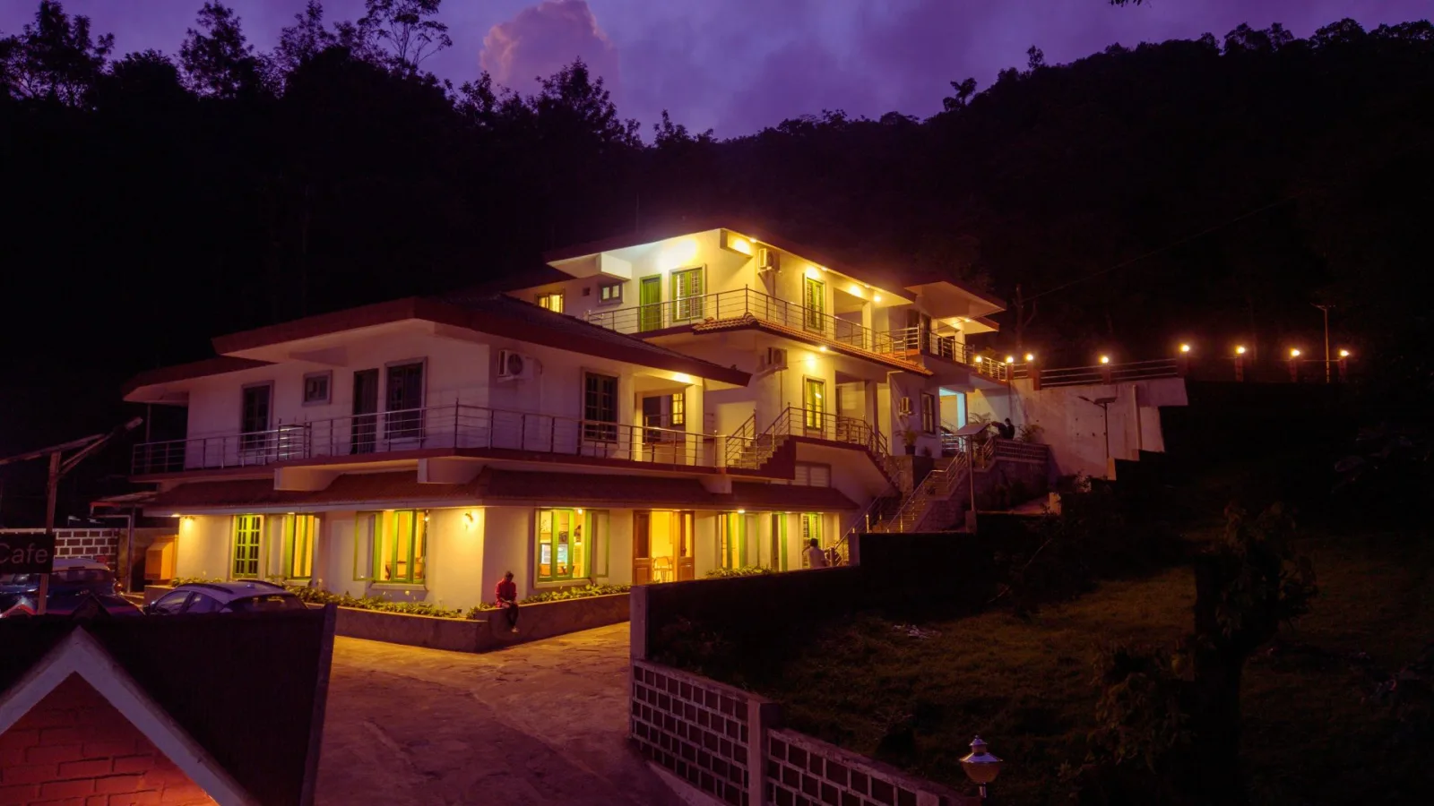 Hasu Stay after dark under a violet sky, warm light spilling from every room