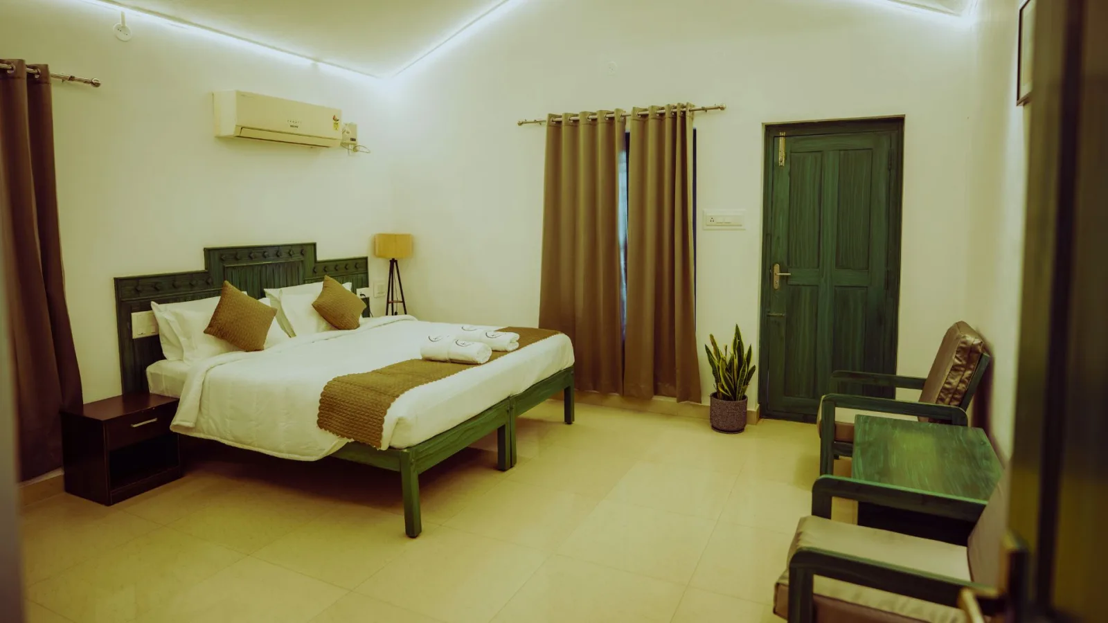 A guest room at Hasu Stay with a carved green bed frame, air conditioning and a seating corner